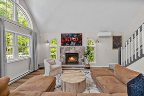 A living room with a stone fireplace, a Netflix sign, and large windows. - Game Room A C Dog-friendly Stay With Hot Tub (Albrightsville)