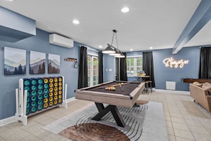A pool table in a room with blue walls, a neon sign, and a view of greenery outside. - Game Room A C Dog-friendly Stay With Hot Tub (Albrightsville)