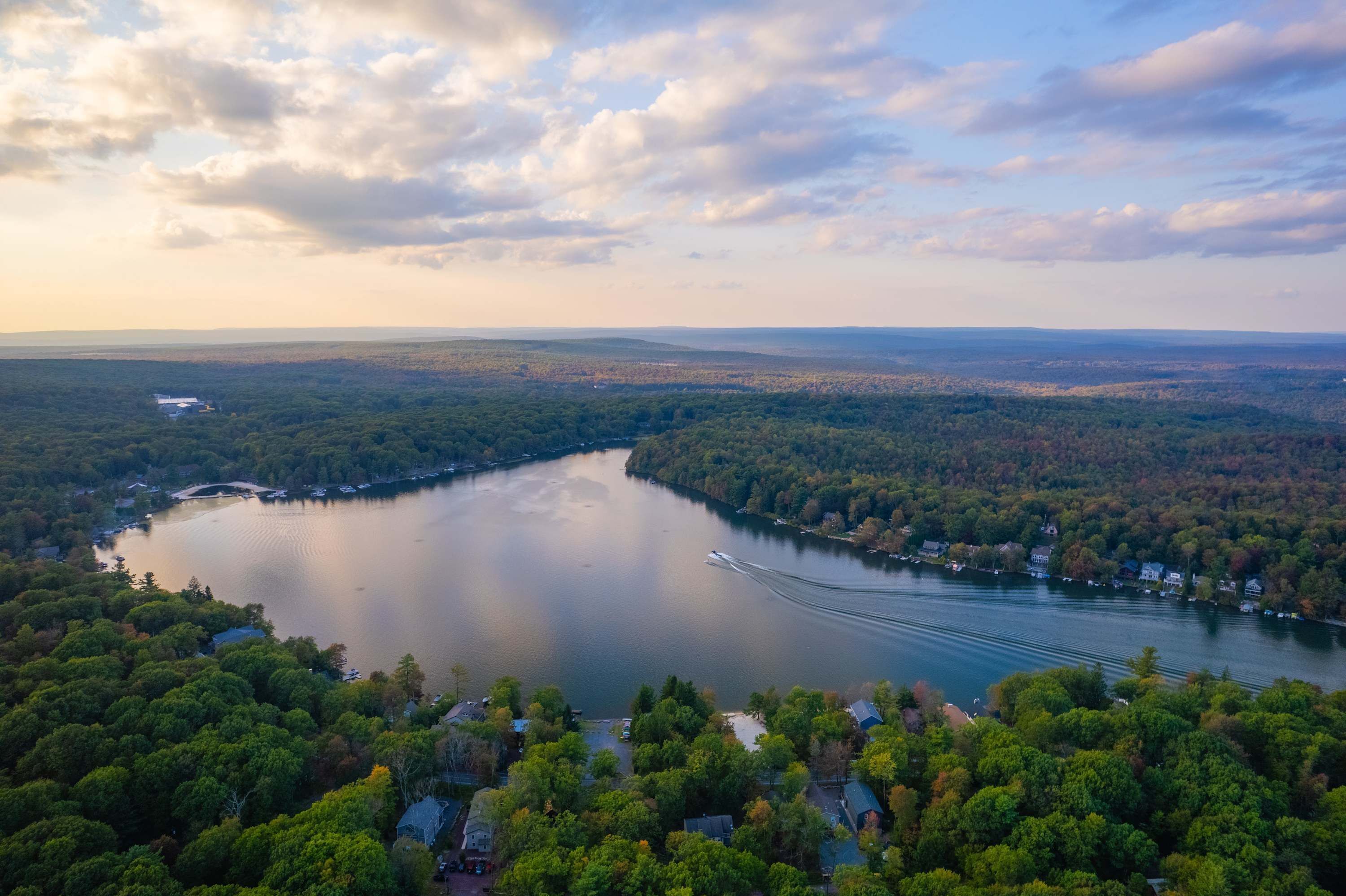 An aerial view of a lake surrounded by dense forest and residential areas.