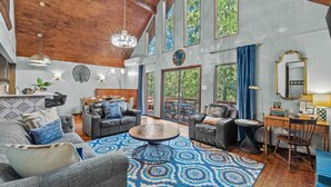 A spacious living area with a large round coffee table, leather sofas, and a dining area with a wooden table and chairs. - Poconos Speakeasy Hot Tub Dog-friendly Near Ski (Lake Harmony)