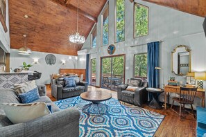 Un vaste espace de vie comprenant un grand salon avec une table basse ronde, des canapés en cuir et un coin repas avec une table et des chaises en bois.