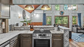 A modern kitchen with a central island, built-in oven, and stainless steel appliances. - Poconos Speakeasy Hot Tub Dog-friendly Near Ski (Lake Harmony)