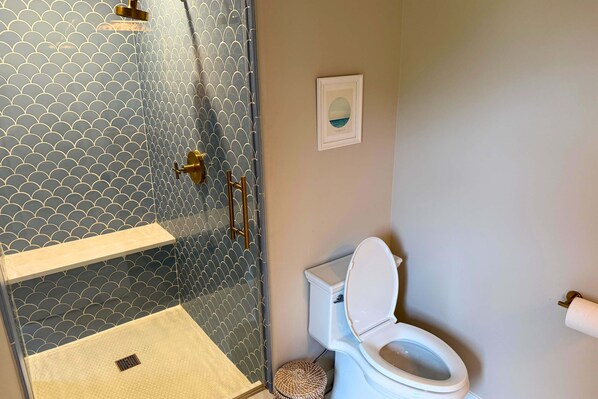 A bathroom with a glass-enclosed shower, a toilet, and a framed picture on the wall. - Modern Chesapeake Waterfront - Heated Pool - Dock (Cambridge)