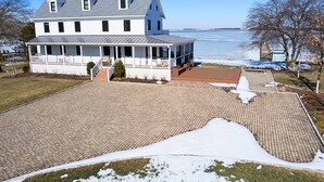 A large white house with a covered porch and a brick patio. - Modern Chesapeake Waterfront - Heated Pool - Dock (Cambridge)