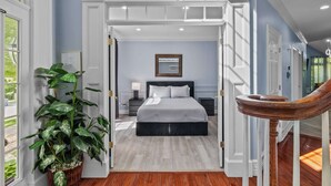 Ein Schlafzimmer mit einem Bett, einem Nachttisch, einer Topfpflanze und einer Treppe.