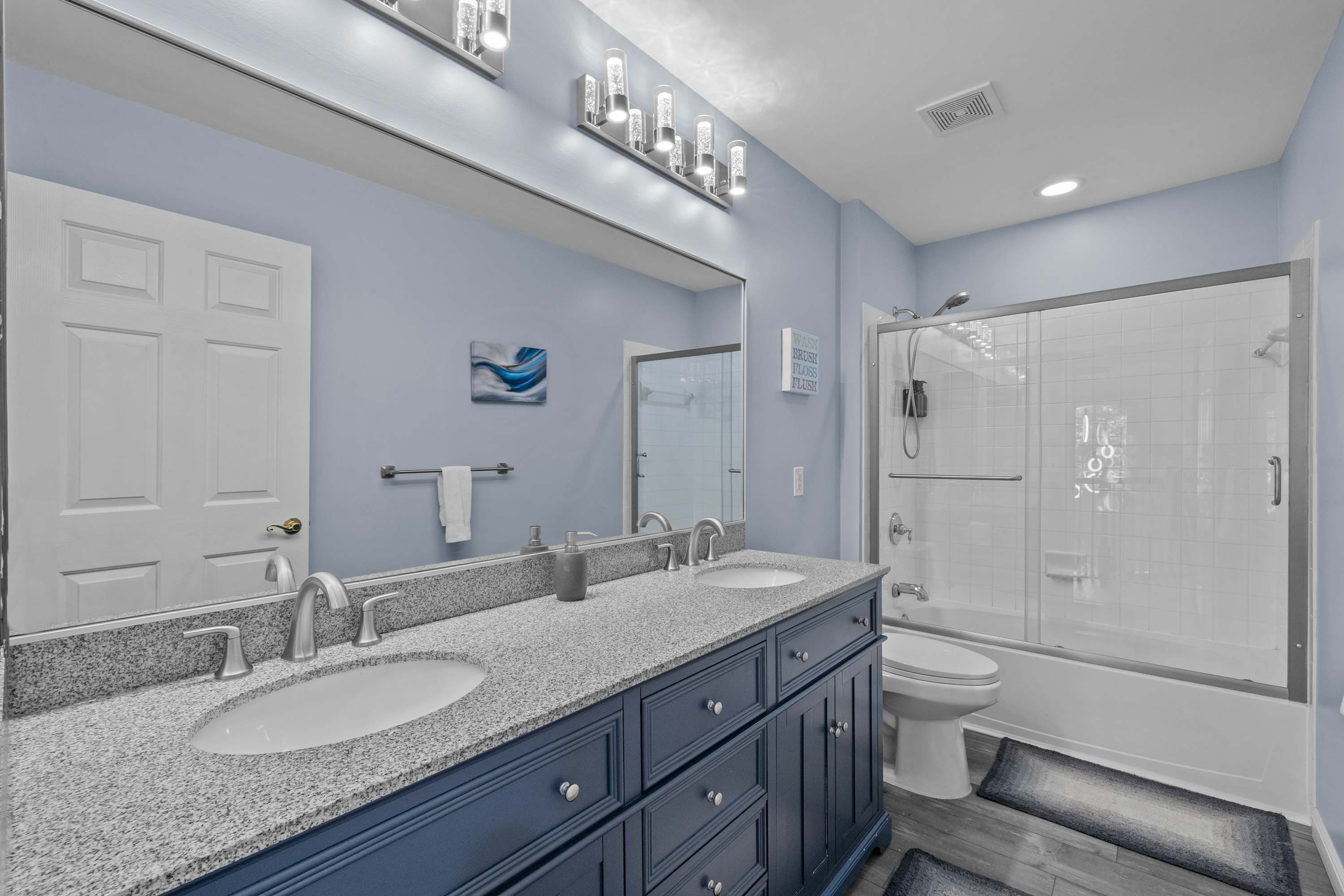 A bathroom with two sinks, a large mirror, a shower, and a towel rack.