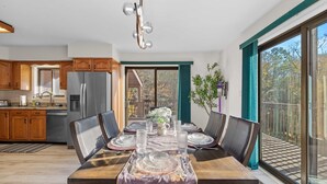 A modern kitchen with wooden cabinets, a stainless steel refrigerator, and a dining area with a table set for six. - Streamside Hot Tub Dog Friendly Resort Access (Pocono Lake)