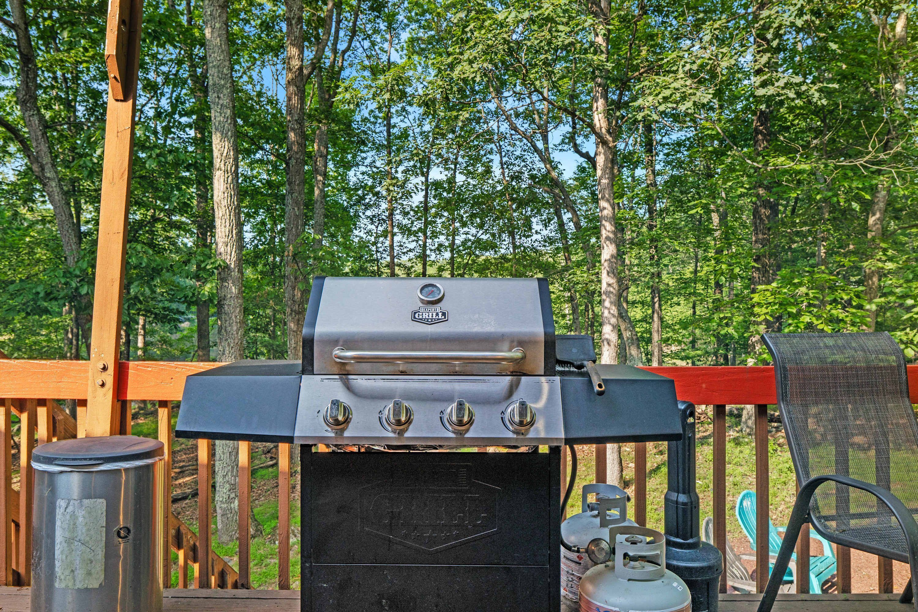 Una parrilla de barbacoa en una terraza de madera con un bosque de fondo.