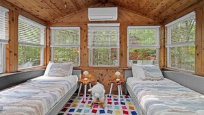 Una cabaña con dos camas, un tapete colorido y techo de madera.
