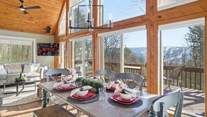 A dining area with a wooden table set for four, a ceiling fan, and a view of the outdoors. - Views of Blue Mountain Near App Trail Game Room (Palmerton)