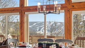 A dining table set with plates, glasses, and a centerpiece, with a view of a snowy landscape through large windows. - Views of Blue Mountain Near App Trail Game Room (Palmerton)