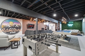 A modern indoor space with a foosball table, a pool table, and a cozy seating area with sofas and a coffee table. - Amenity-filled Retreat by Jfbb-pickleball-gameroom (Albrightsville)