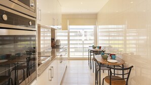 Et moderne køkken med spiseplads, stort vindue, rustfrie stålemmer og minimalistisk indretning.