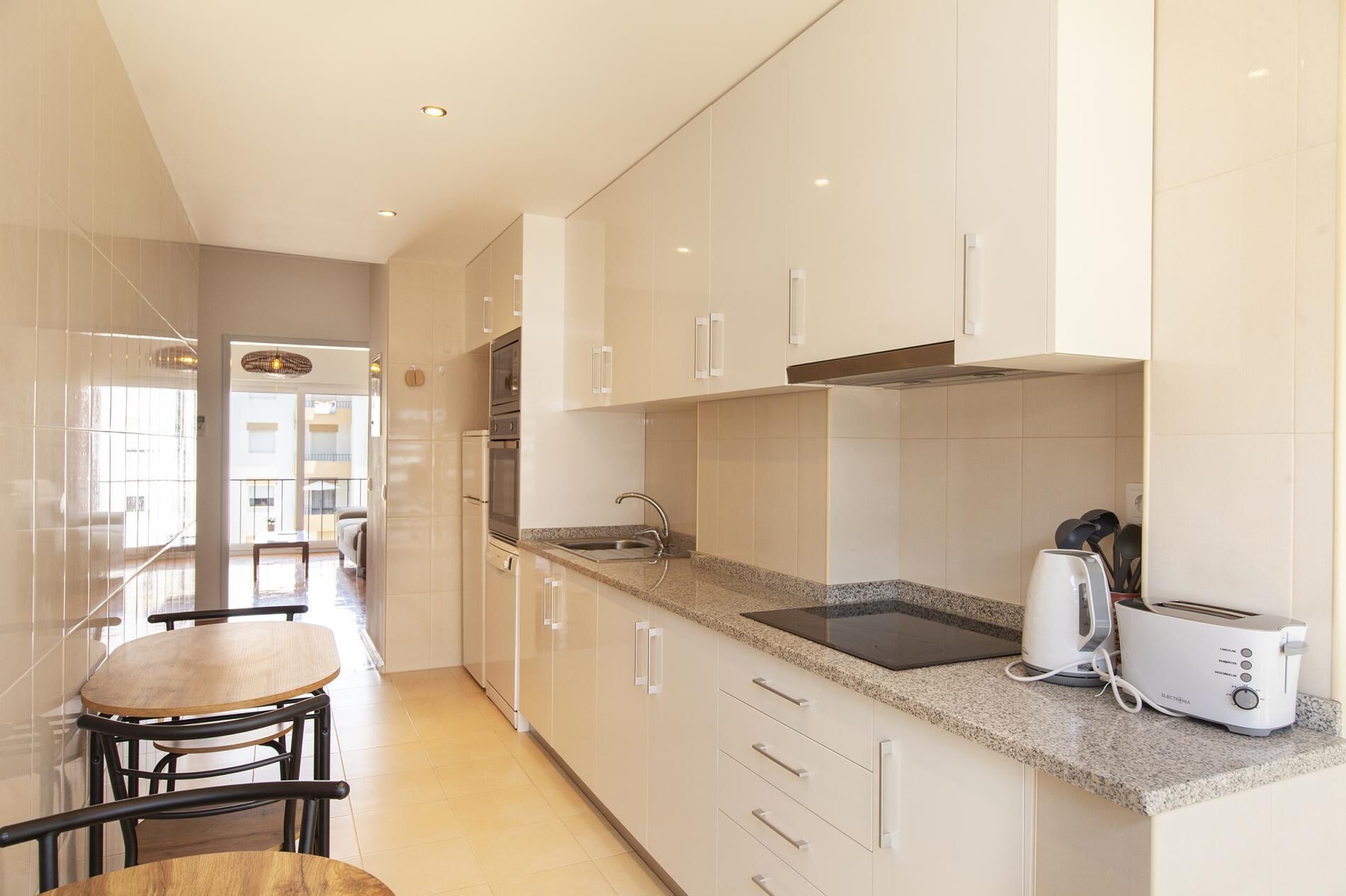 Een moderne keuken met witte kasten, een granieten aanrecht, een ingebouwde oven, een spoelbak en een broodrooster.