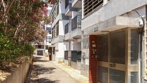 Eine schmale Straße mit Gebäuden, einem verschlossenen Eingang und einem Haus mit einer großen Glasdoor.