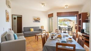 Un salon avec un canapé, une table à manger dressée et un téléviseur.
