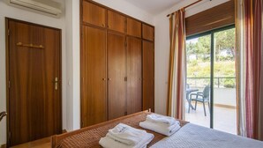 Une chambre à coucher avec un lit, une armoire et un balcon équipé de chaises.