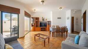 Un salon comprenant un canapé, une table basse, un téléviseur et un coin repas avec une table et des chaises.