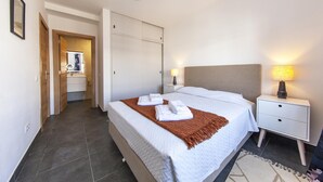 A hotel room with a bed, bedside lamps, a nightstand, a wardrobe, and a bathroom visible through an open door. - B74 - Baluarte Holiday Flat in Lagos (Lagos)