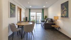 A modern living room with a sofa, a dining table with chairs, a TV, and artwork on the walls. - B74 - Baluarte Holiday Flat in Lagos (Lagos)