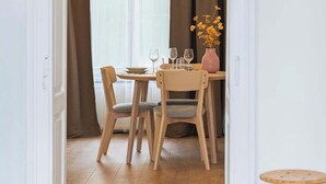 Un espace repas comprenant une table, des chaises, un vase avec des fleurs et un luminaire suspendu.