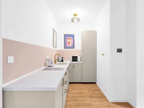 A compact kitchen with a white countertop, a coffee maker, a toaster, and a microwave. - Trendy Apartment in Centrum 2 (Bratislava - Old Town)