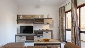 Un soggiorno moderno con televisore, mensole in legno, tavolino e divano.