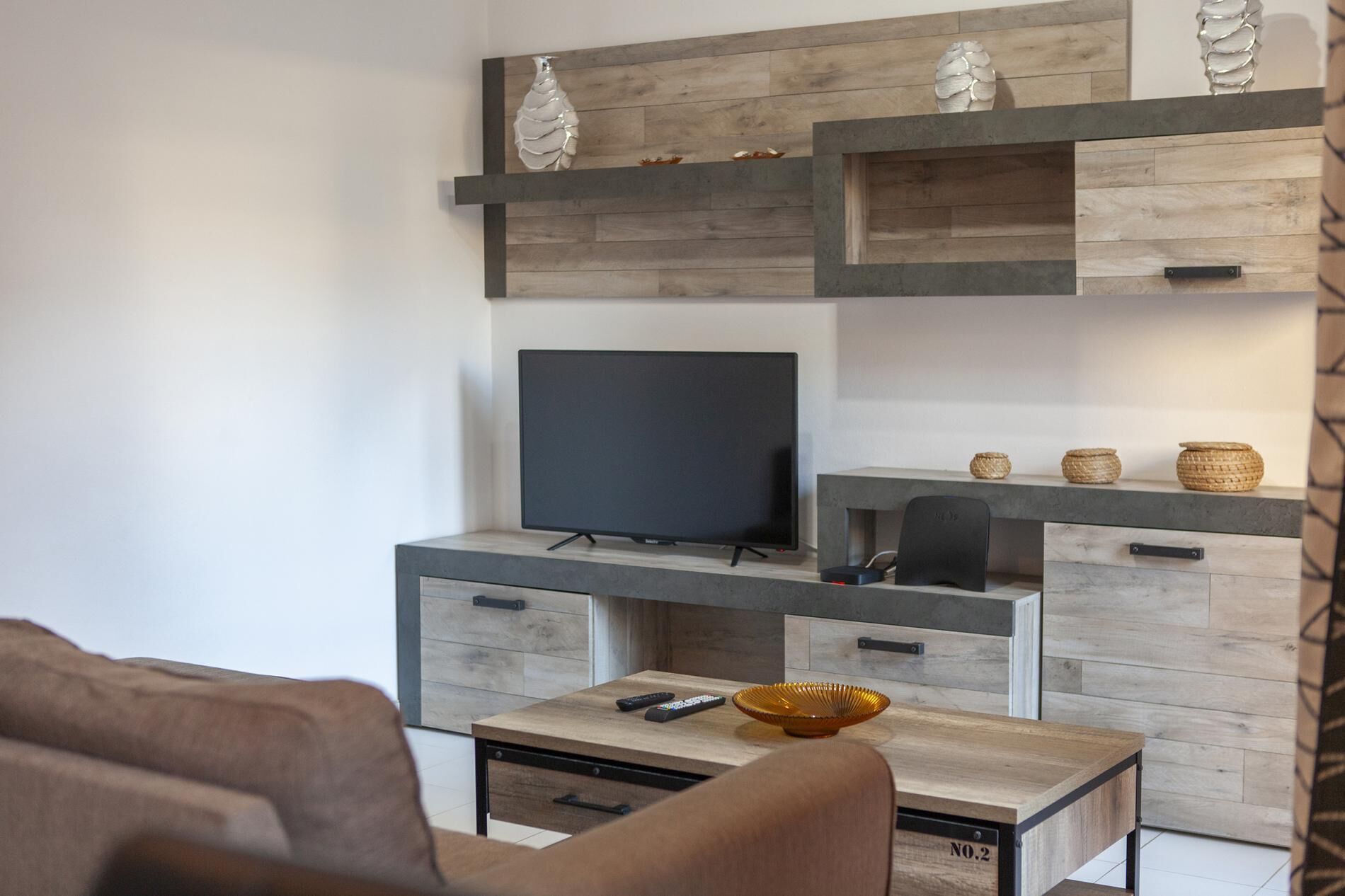 A modern living room with a TV, wooden cabinets, a coffee table, and a sofa.