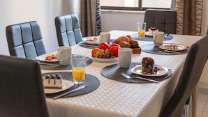 Una colazione con un tavolo apparecchiato per quattro persone, con piatti di cibo, bevande e posate.