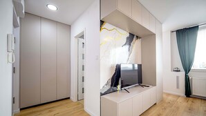 A modern room with a built-in TV, wooden flooring, a white wardrobe, and a window with curtains.