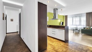 Una cocina moderna con armarios blancos, una campana extractora de acero inoxidable y una puerta de color marrón oscuro.