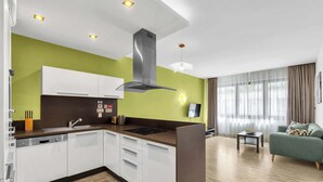 Una cocina moderna con armarios blancos, una campana extractora de acero inoxidable y un lavavajillas integrado.