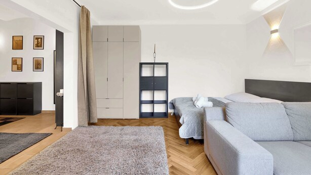 Een moderne woonkamer met een bank, een televisie, een boekenkast en een decoratieve lamp.