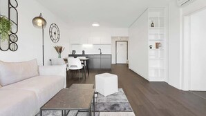 A modern living room with a sofa, coffee table, and a dining area with chairs. - Urban White Oasis in Centre (Bratislava - Old Town)