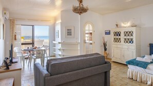 A room with a dining area, a sofa, a cabinet, and a view of the sea. - A73 - Iberlagos Studio Flat (Lagos)
