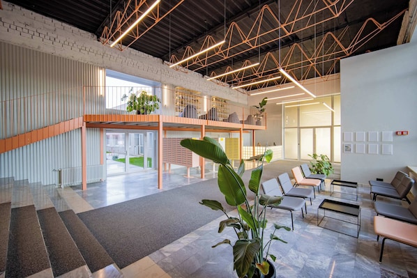 A modern interior with a mezzanine level, seating area, and a staircase.