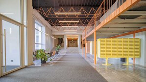 A spacious hallway with a staircase, a yellow information desk, and a potted plant. - Cozy Hideaway Studio with Balcony (Košice)