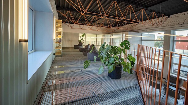 A modern interior with a metal staircase, large windows, and a hanging copper structure. - Cozy Hideaway Studio with Balcony (Košice)