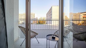 A balcony with two chairs and a small table, overlooking a parking lot and buildings. - Cozy Hideaway Studio with Balcony (Košice)