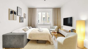 Una camera d'albergo moderna con un letto, una scrivania, una TV e una finestra con tende.