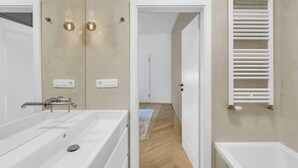 Un bagno moderno con una vasca da bagno ampia, un portasciugamani bianco e uno specchio.