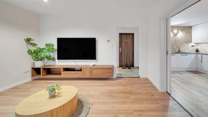 Un soggiorno moderno con televisore a schermo piatto, mobile contenitore in legno e un tavolino tondo con una pianta.