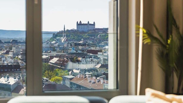 Ein Zimmer mit großem Fenster, einer Couch und Blick auf ein Schloss.