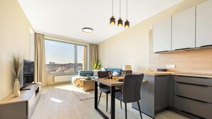Eine moderne Wohnung mit Essbereich, Küche und großen Fenstern mit Blick auf die Stadt.