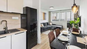 A modern kitchen with a black refrigerator, a wooden countertop, and a dining area with a table set for two.