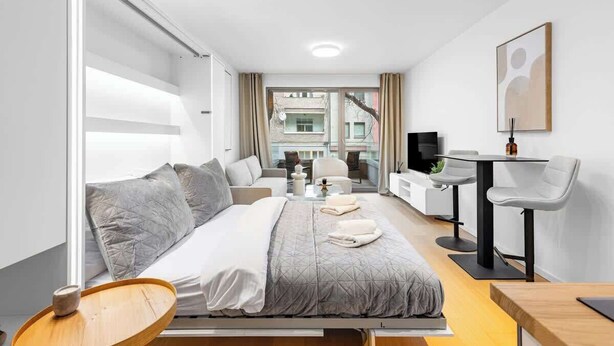Habitación de hotel moderna con cama, escritorio, silla y vistas a la ciudad.