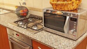Une cuisine équipée d’une cuisinière à gaz, d’un four, d’un four à micro-ondes, d’un plan de travail en granit et d’armoires en bois.