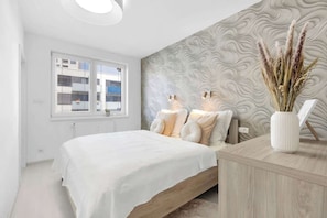 Un dormitorio moderno con una cama, mesitas de noche, una ventana y una pared con textura.