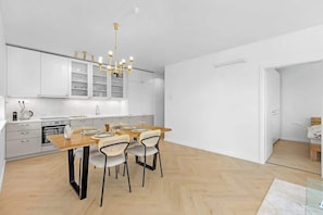 Una cocina moderna con armarios blancos, una mesa de comedor de madera y cuatro sillas.