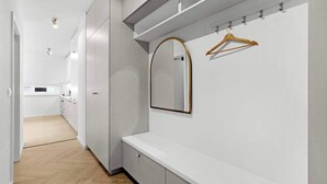 Een moderne badkamer met een spiegel, een houten kapstok en een wit aanrecht.